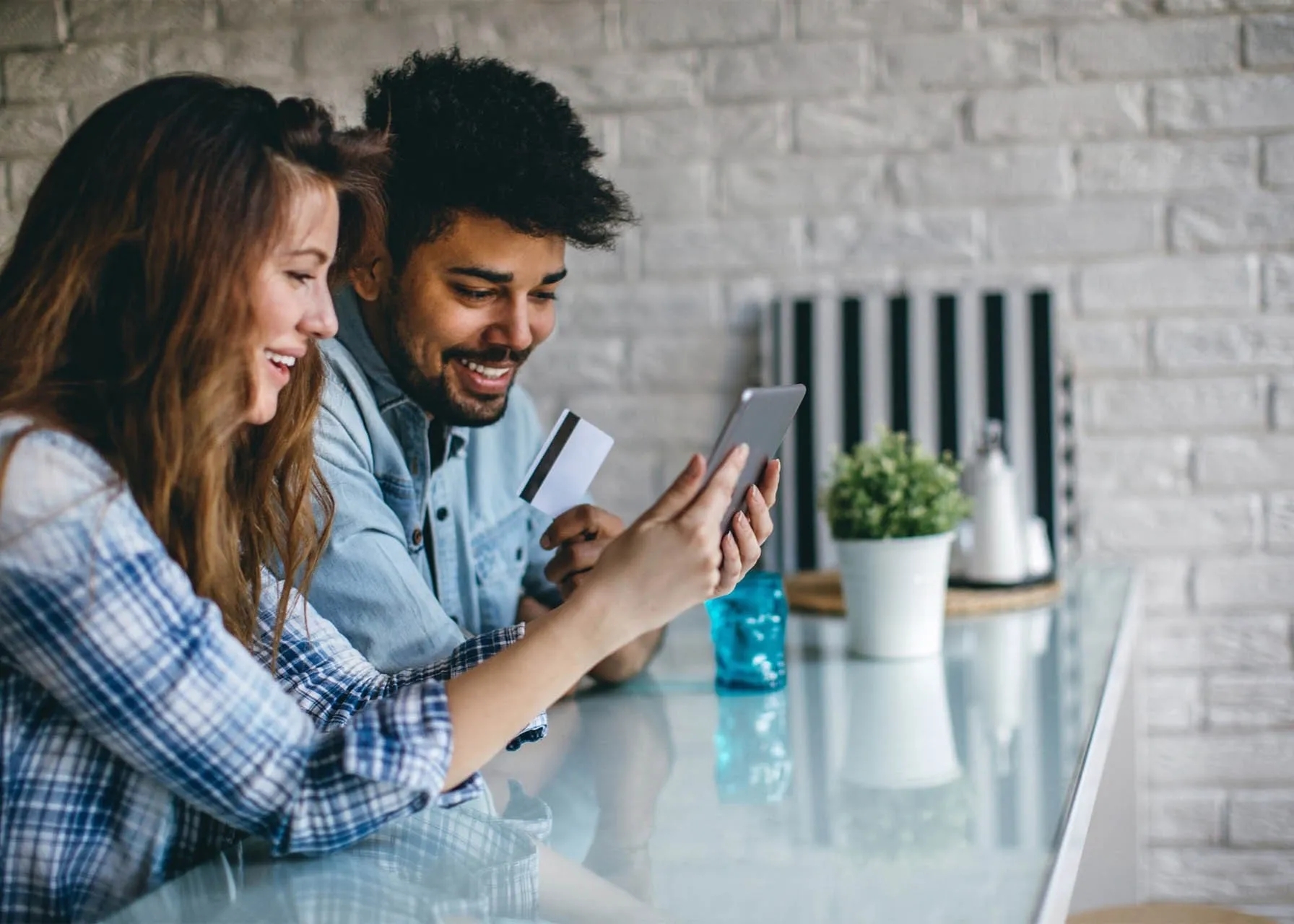 Two people holding and viewing a tablet, holding a credit card in another hand.