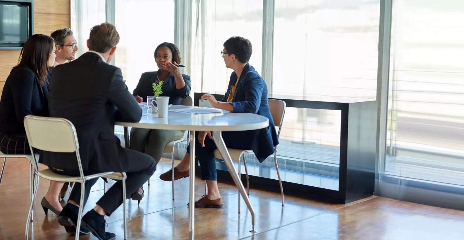 A team have a discussion in a modern, well lit meeting room.