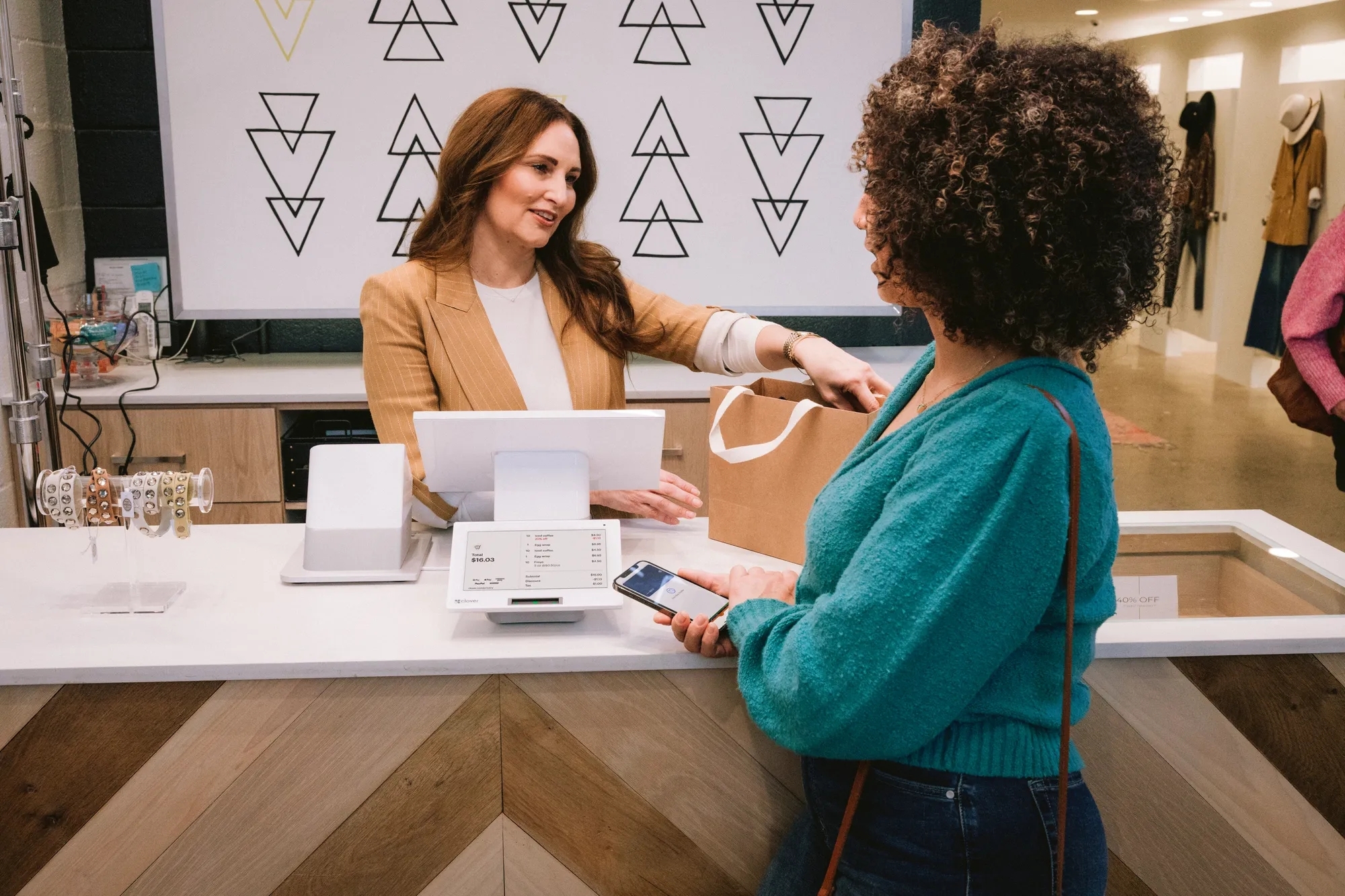 Saleswoman handing a clothing bag to another woman