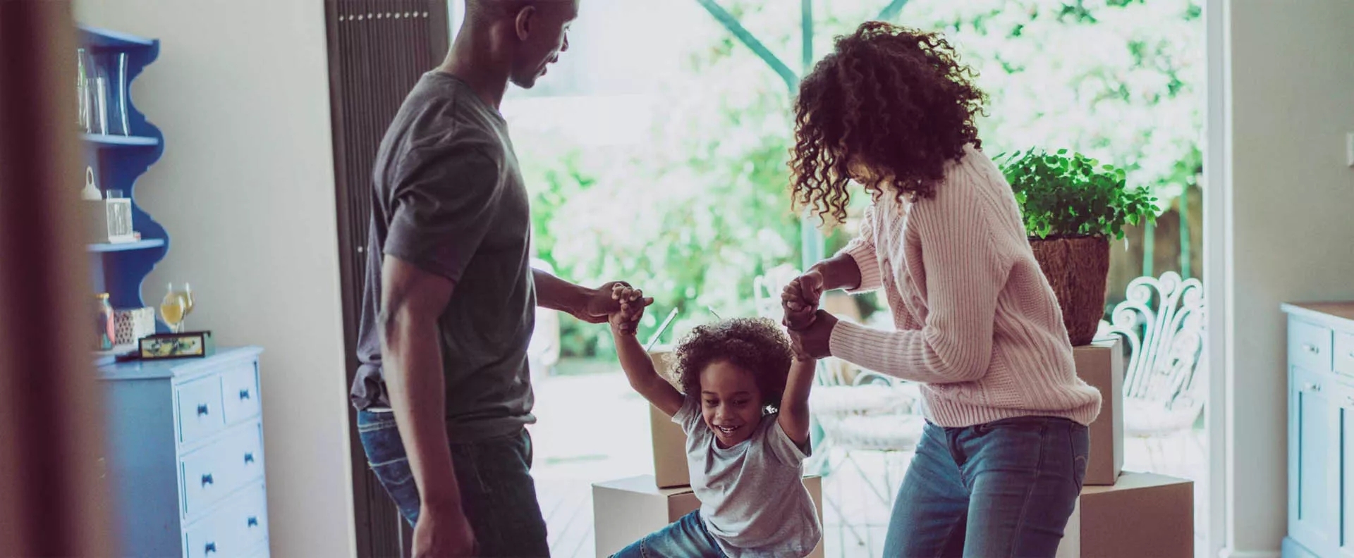 Man and a women holding hands of a child helping her walk.